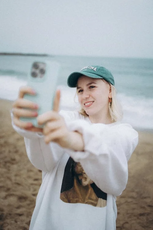 a woman with a phone at the beach.