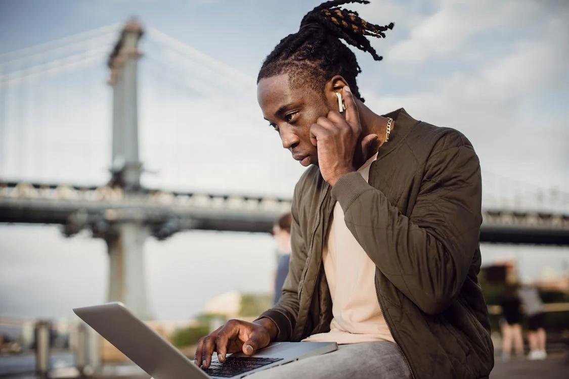 a man sitting outdoors and talking on the phone.
