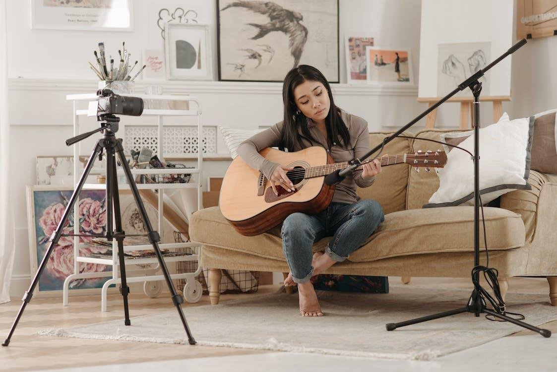 A woman recording herself playing the guitar