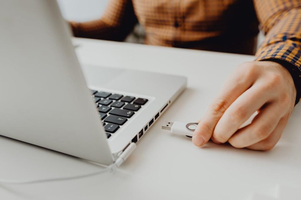 A person inserting a flash drive into a laptop