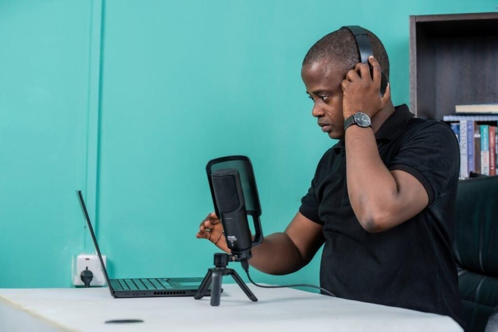 A person sitting at a table with a laptop and a microphone