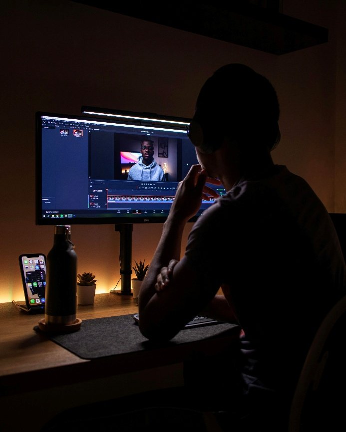 A young creator sitting in front of a large screen while editing video content