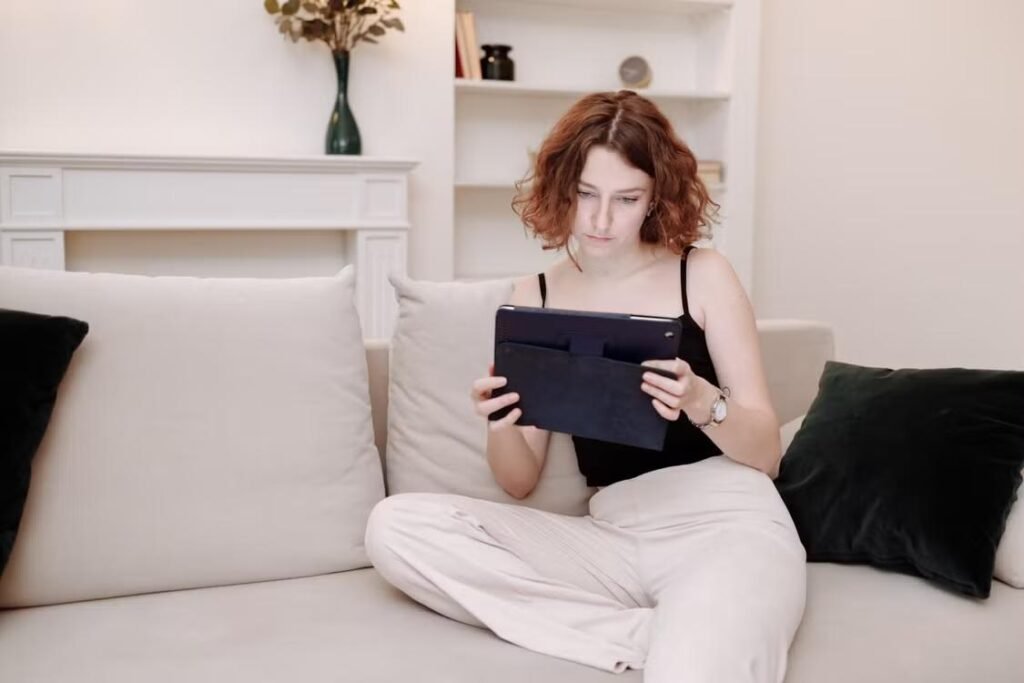 A person sitting on a couch and holding a tablet