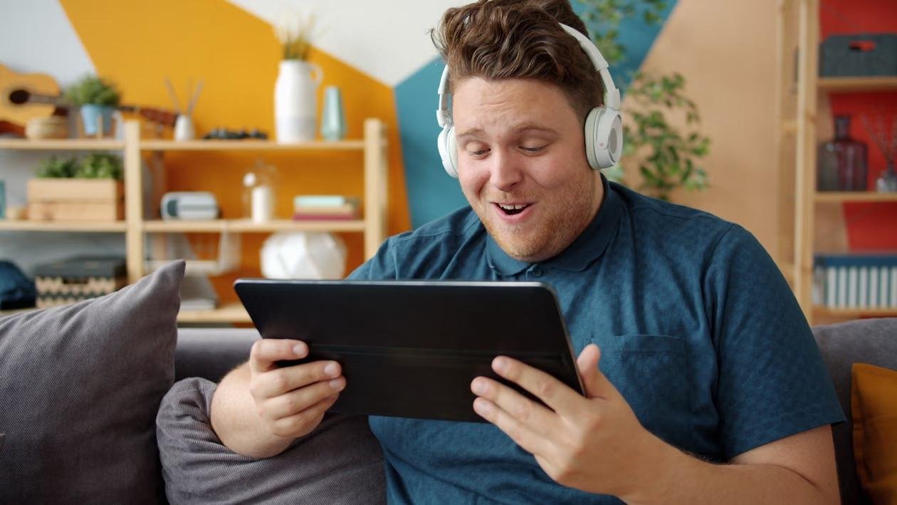 A person watching a tablet while wearing headphones